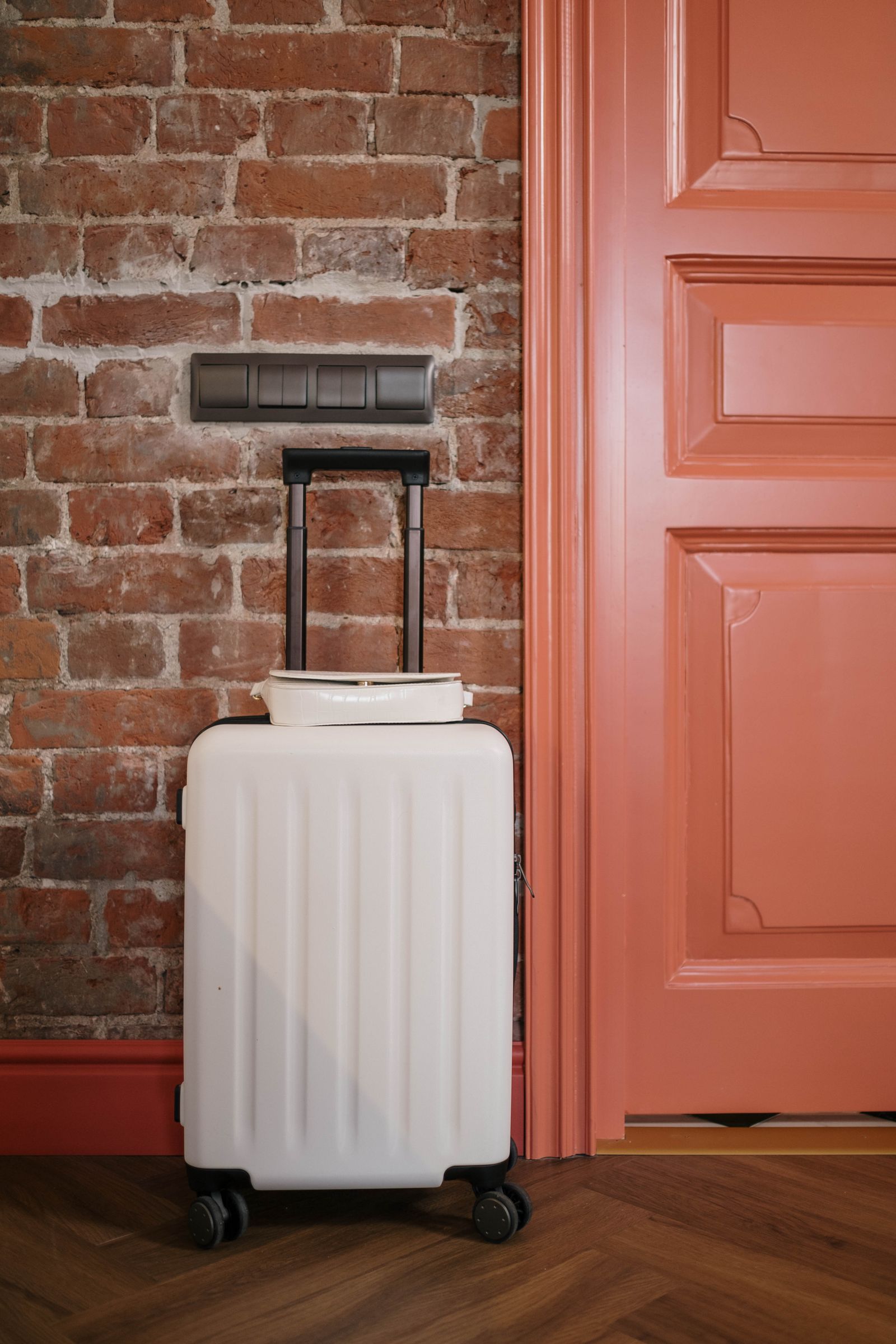 Una maleta blanca preparada junto a la puerta de entrada de una casa