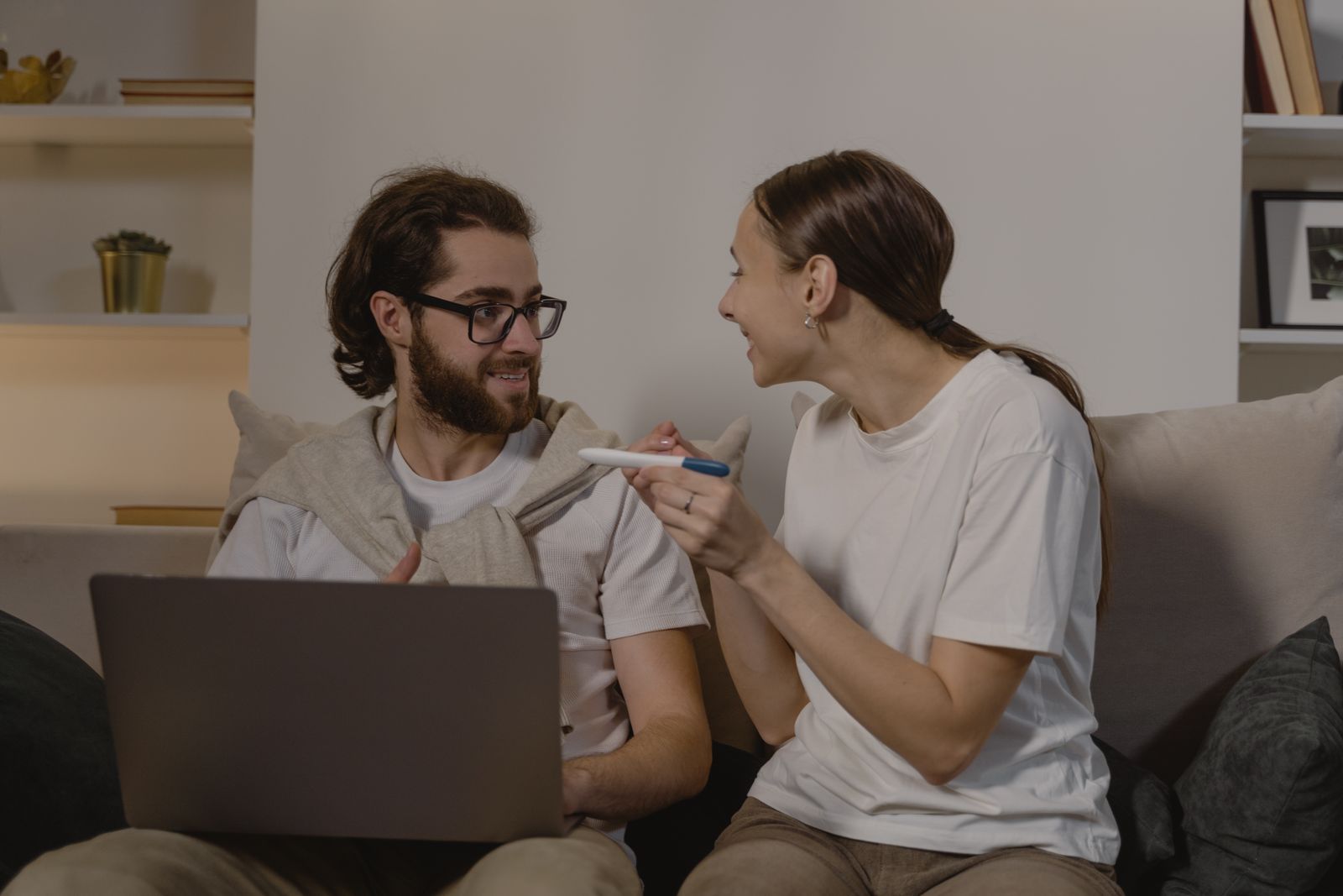 Pareja sonriente en el sofá de casa compartiendo un momento de esperanza