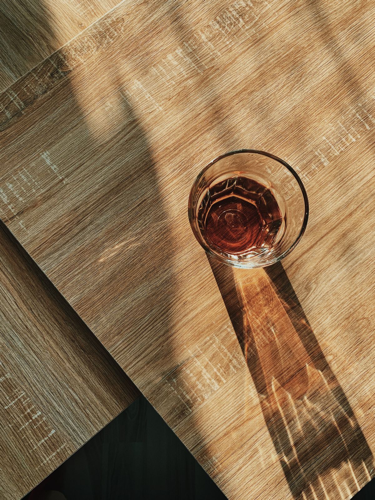 Un vaso de cristal sobre una mesa de madera iluminada por el sol de la mañana