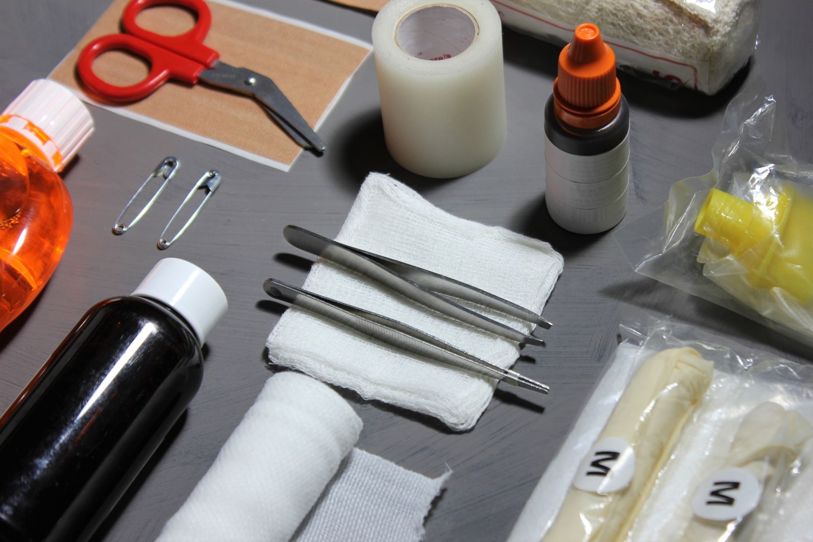 Material de cura sobre una mesa: gasas, pinzas, esparadrapo y vendas